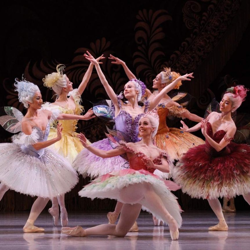 Ballet dancers in colorful tutus performing together on a stage