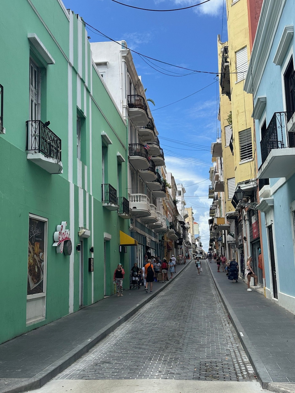 Narrow street lined with colorful pastel colonial buildings in Puerto Rico under blue sky