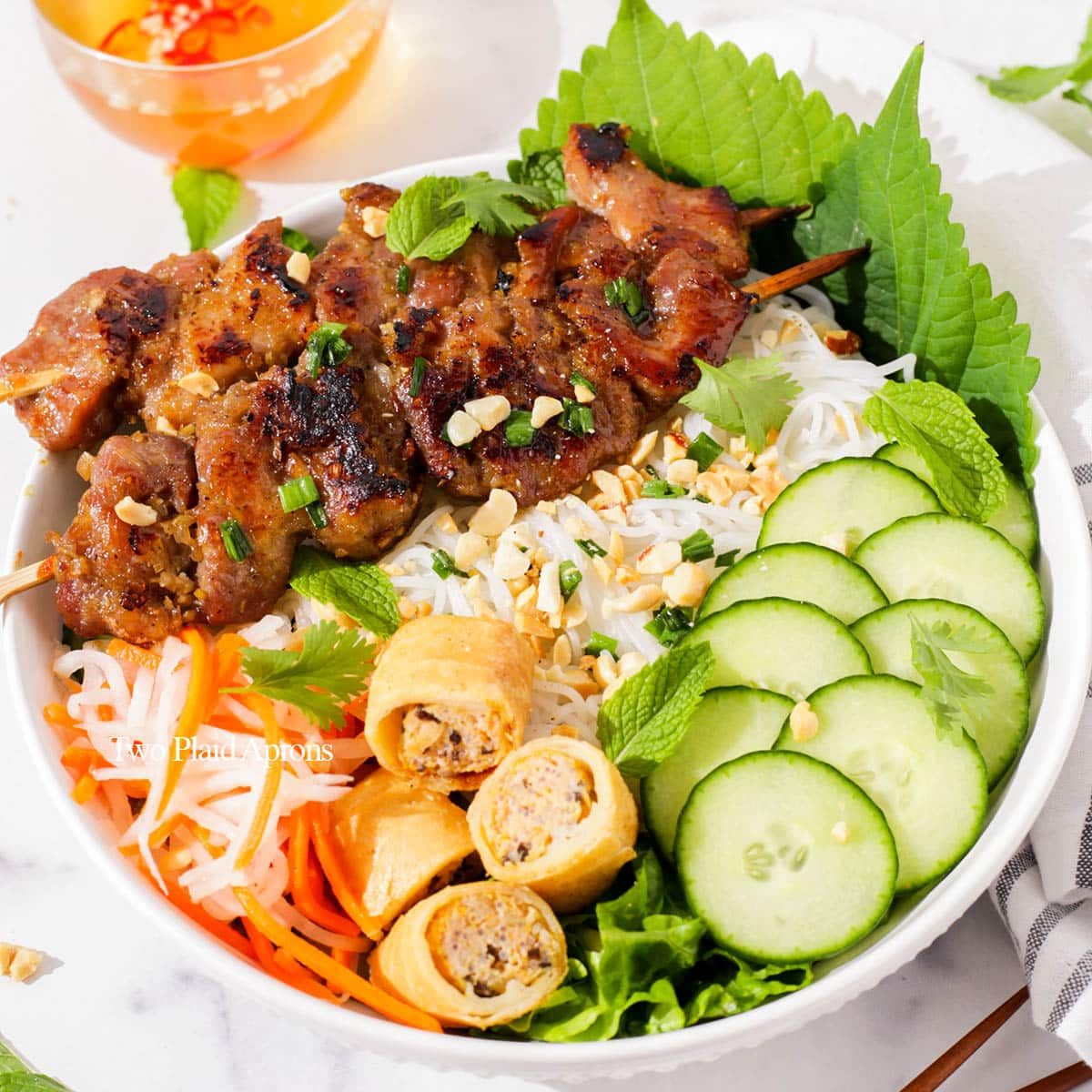 Vietnamese grilled pork vermicelli bowl with fresh vegetables and herbs in white bowl