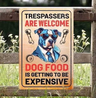 Funny yard sign with illustrated dog wearing suit and sunglasses, humorous warning about trespassing and dog food costs