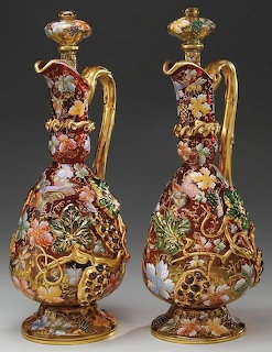 Two ornate antique porcelain ewers with gold handles and colorful floral enamel decoration