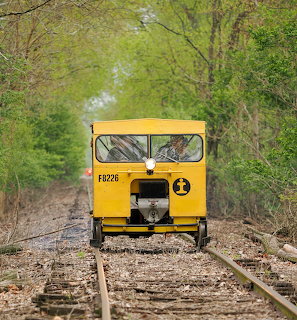 Yellow railway speeder on tracks in wooded area