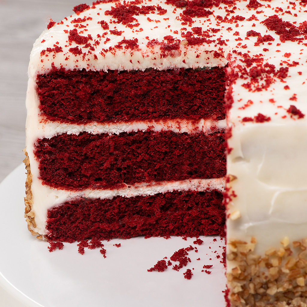 Close-up of a sliced red velvet layer cake with white frosting on a plate