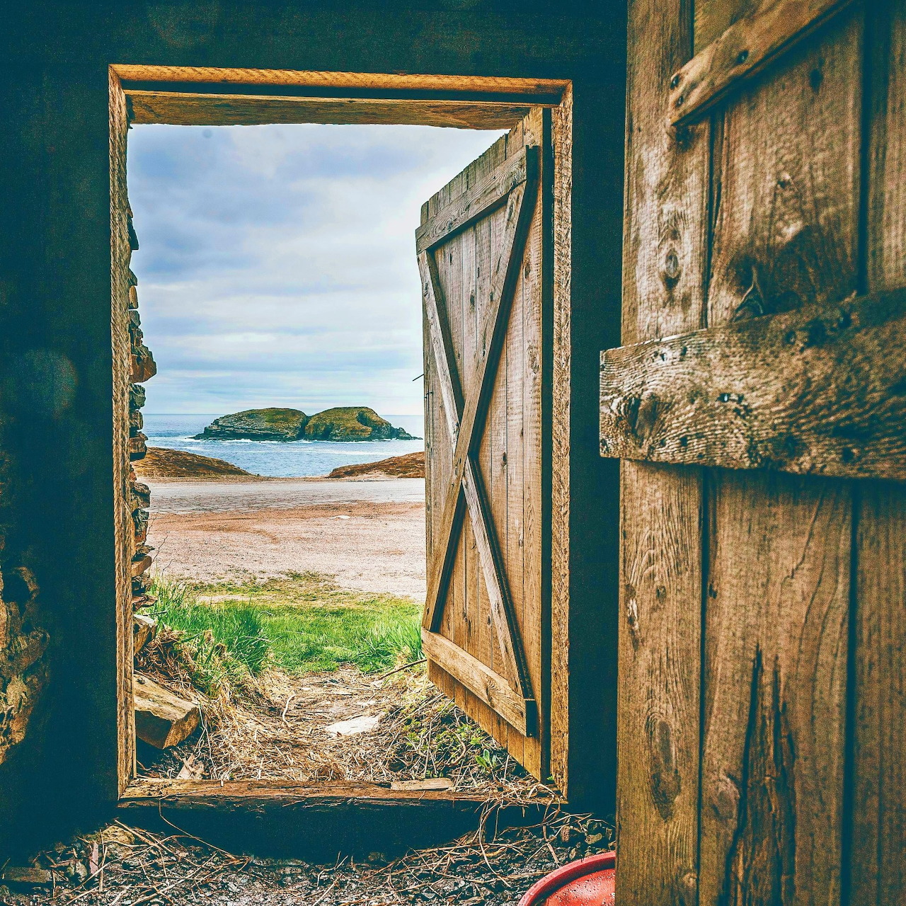 Open rustic door framing a beach view with island and ocean