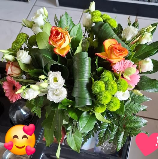 Colorful mixed flower bouquet with roses, white flowers, green blooms, and leafy foliage