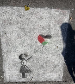 Chalk drawing of girl reaching toward red and green heart balloon on gray pavement with shadow
