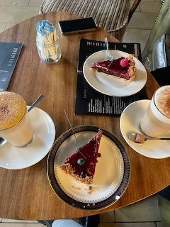 Two slices of cherry cake with coffee drinks on a wooden café table