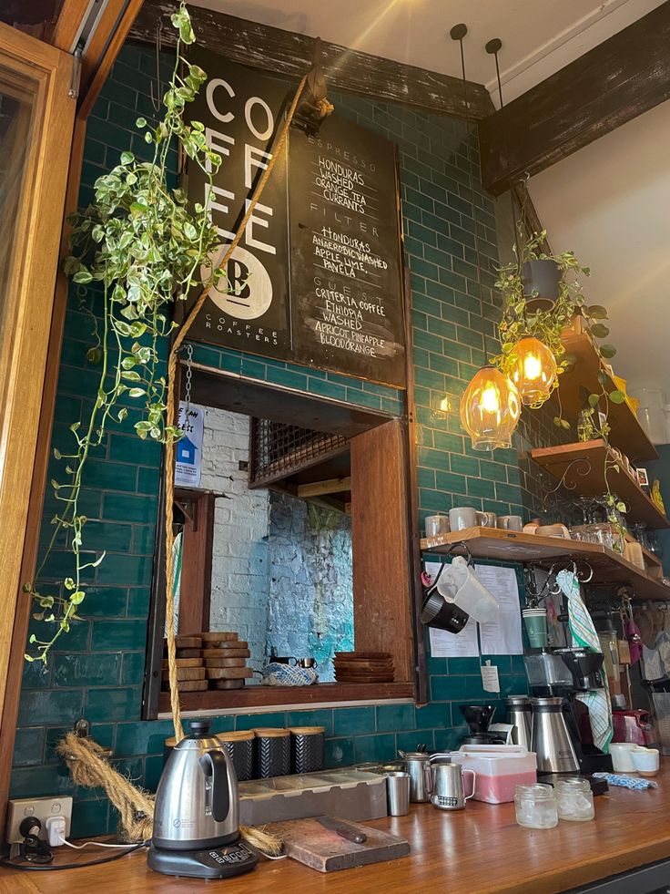 Cafe counter with teal green brick wall, trailing plants, warm pendant lights and coffee equipment