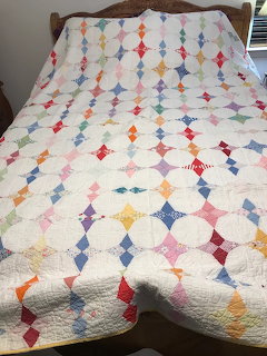 Colorful vintage feed sack quilt with star pattern displayed on a bed