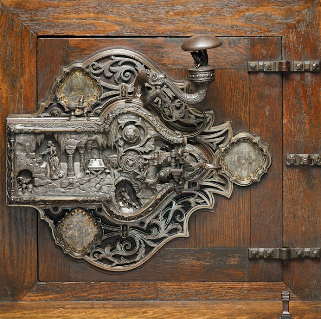 Antique metal doorknob and ornate lock plate on a rustic wooden door