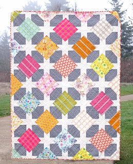 Colorful patchwork quilt with diagonal square blocks in various bright fabrics on white geometric grid background