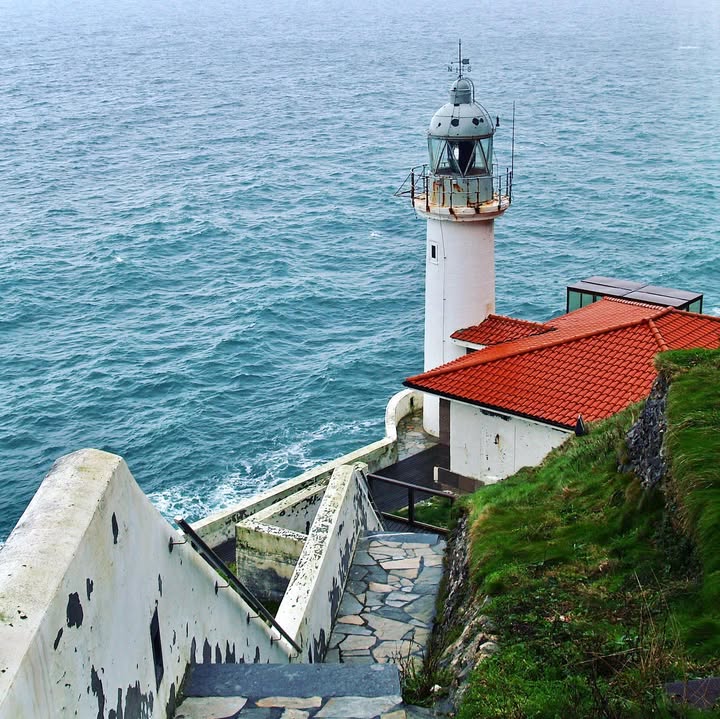 White lighthouse on a coastal cliff overlooking the blue ocean