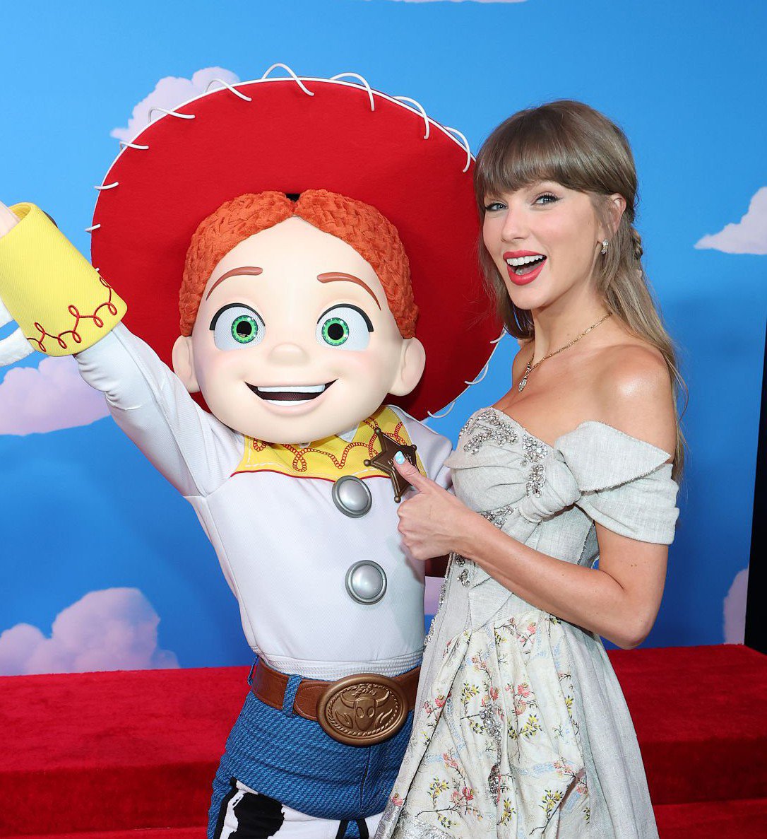 Taylor Swift standing next to Jessie from Toy Story at a film premiere.