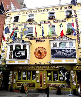 Yellow pub building with traditional Irish music signs and colorful flags on the facade