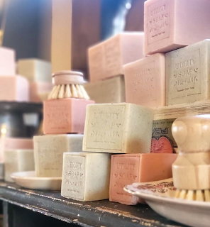 Stacked pastel-colored French soap blocks with embossed text on dark surface