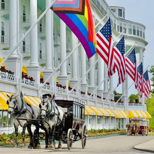 White columned Grand Hotel porch with horse carriages and American flags