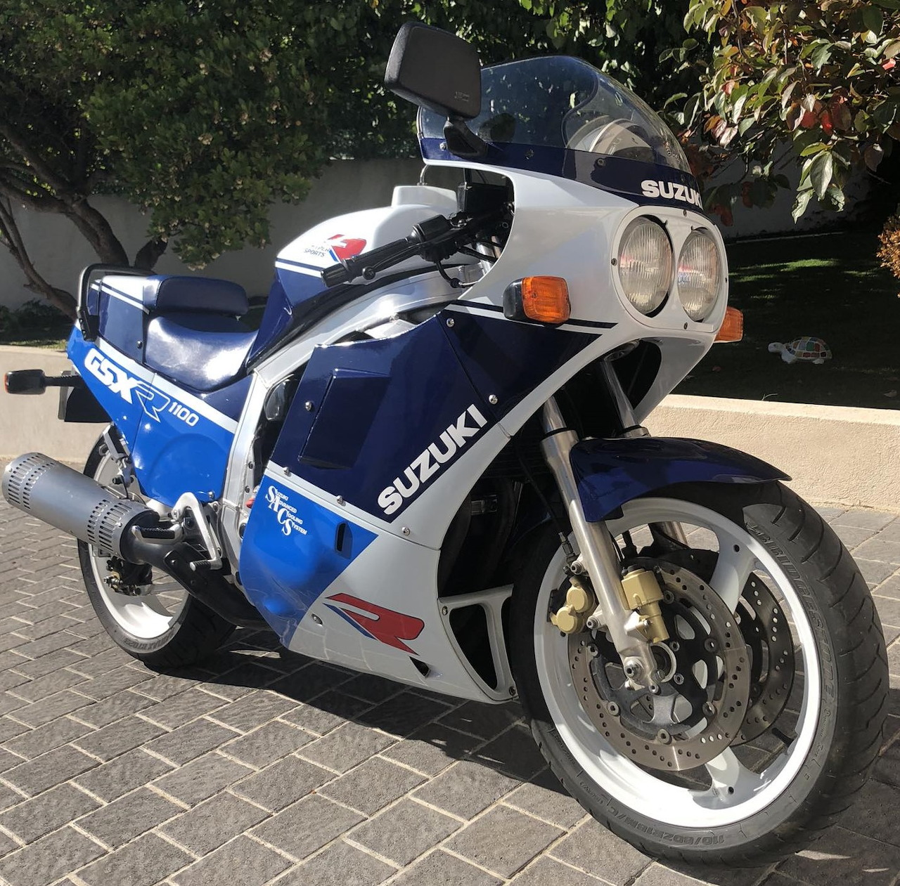 Blue and white Suzuki GSX-R 1100 sport motorcycle parked outdoors on a paved driveway