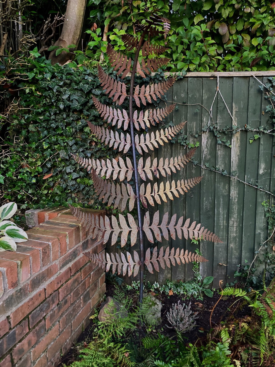 Handcrafted metal fern sculpture with curled frond design