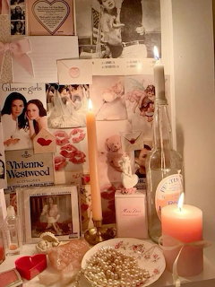 Coquette vanity setup with lit candles, pearls, perfume, and a pink aesthetic photo collage