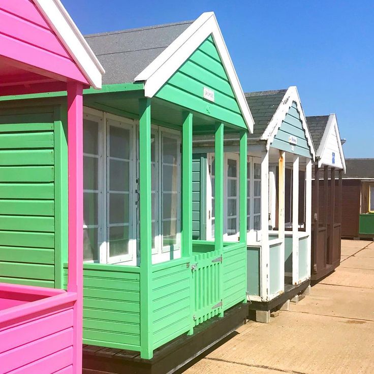 Colorful beach huts in a row with pink, green, white and blue painted wooden fronts