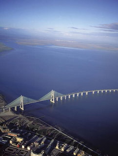 Aerial view of suspension bridge crossing blue water with land and sky