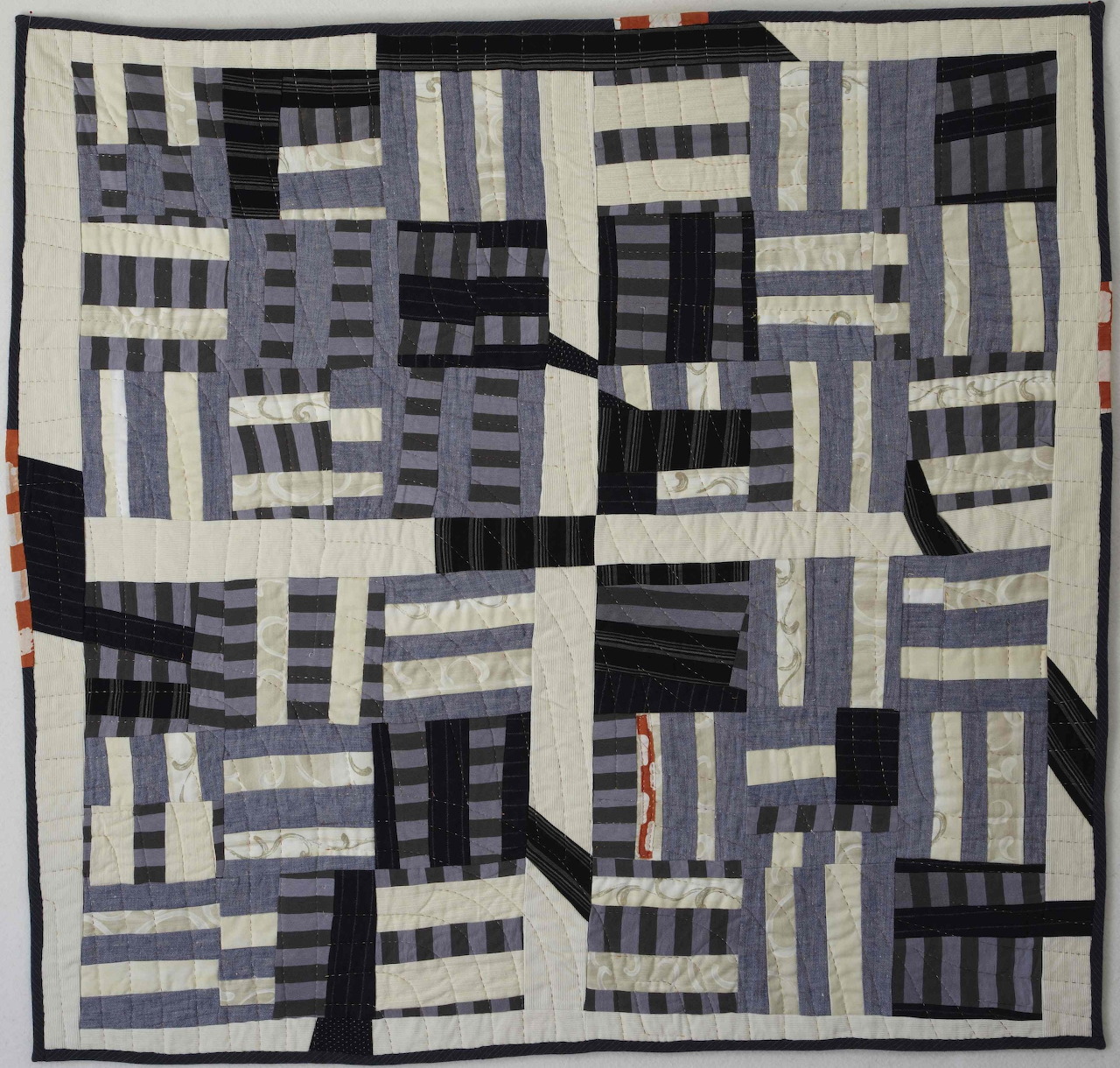 Abstract patchwork quilt in blue, white, and black with striped rectangular blocks