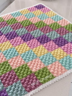 Colorful pastel crochet blanket with diagonal shell stitch pattern and white scalloped edge