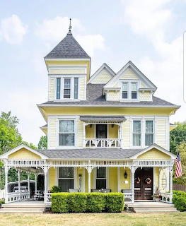 Yellow and white Victorian house with turret and wraparound porch