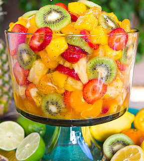Colorful fruit salad in a glass pedestal bowl with strawberries, kiwi, mango, and other tropical fruits