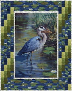 Panel quilt with a great blue heron standing in a pond surrounded by blue and green patchwork borders
