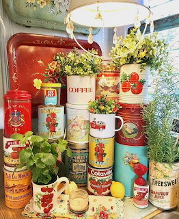 Vintage kitchen tins and containers displayed on white shelves with plants and decorative items