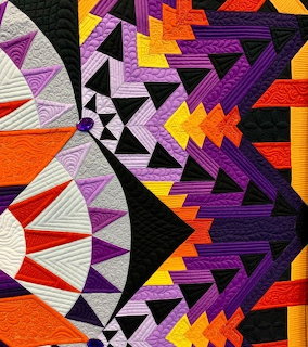 Colorful geometric quilt pattern in purple, orange, black, white, and yellow