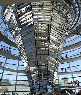 Glass dome interior with mirrored central cone and spiral ramps with people walking