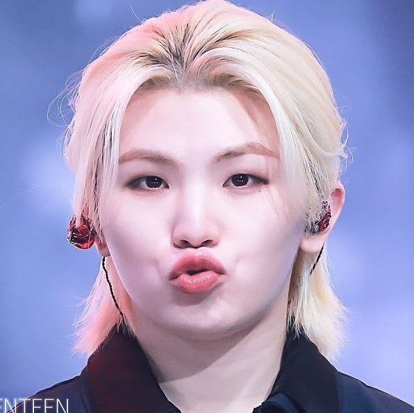 Close-up portrait of Lee Jihoon with blond hair, stage earpiece, and a puckered expression