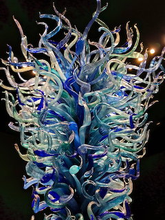 Colorful blown glass sculpture with curling blue and teal tendrils illuminated at night