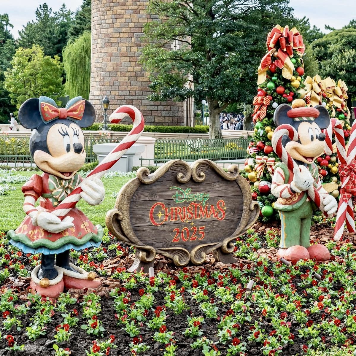 Mickey and Minnie Mouse Christmas statues with holiday decorations and festive sign in Disney park setting
