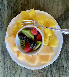 Plate of pineapple, melon, kiwi, strawberries, blackberries, and raspberries on a marble table
