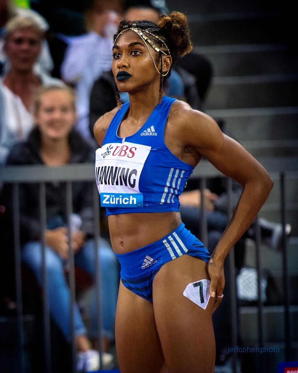 Female track athlete in blue Adidas uniform standing at competition venue