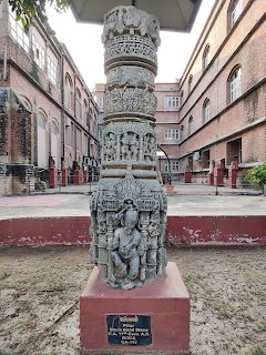 Ornate carved stone pillar monument with detailed sculptures and patterns on display in courtyard