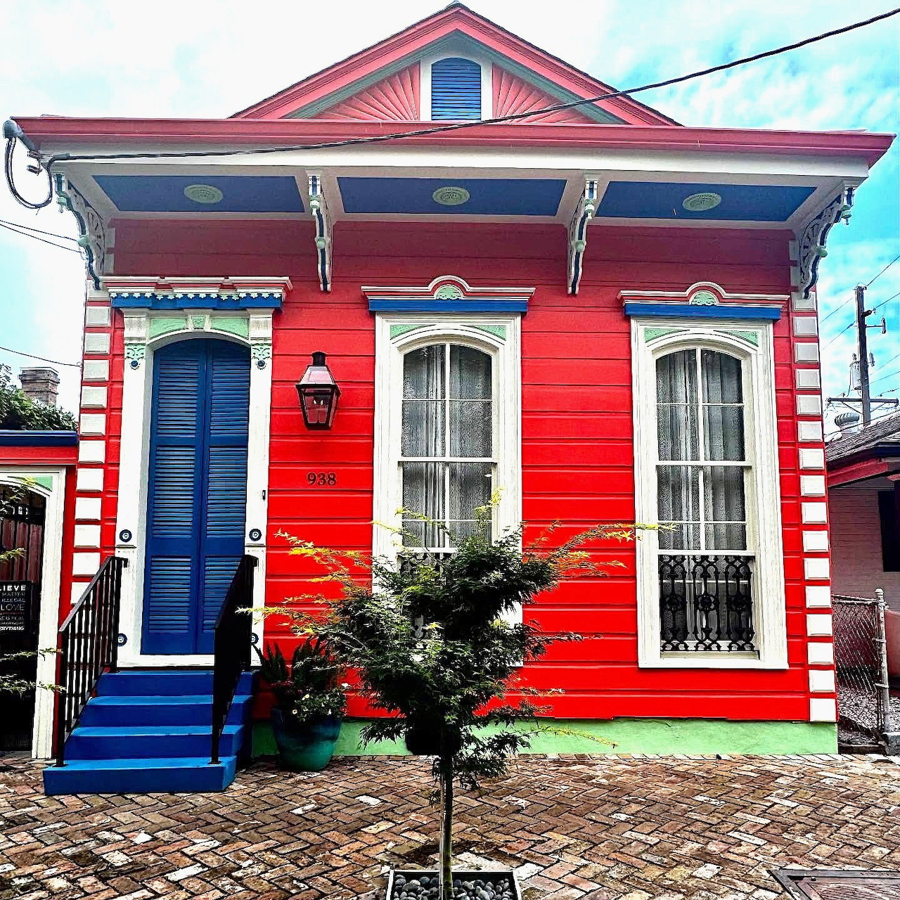 Bright red traditional house with blue door and white ornamental trim under turquoise sky