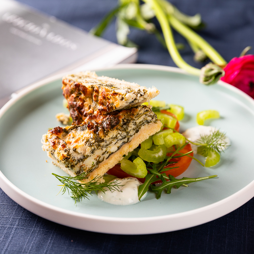 Grilled fish fillet with herbs on white plate with vegetables and garnish