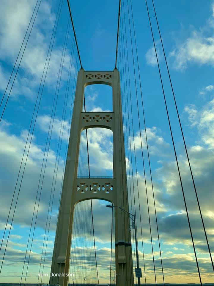 Suspension bridge tower with cables against a blue cloudy sky