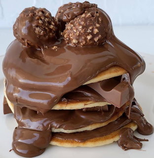 Pancake stack covered in chocolate sauce with two chocolate truffles on top