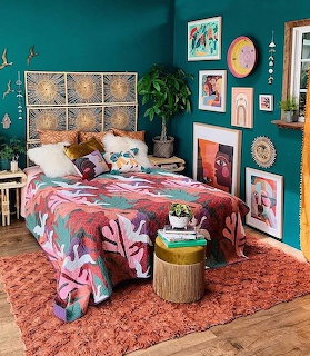 Colorful bohemian bedroom with teal walls, woven headboard, patterned blanket, and gallery wall art