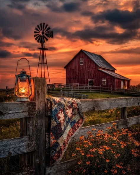 Red barn and windmill at sunset with lantern on fence