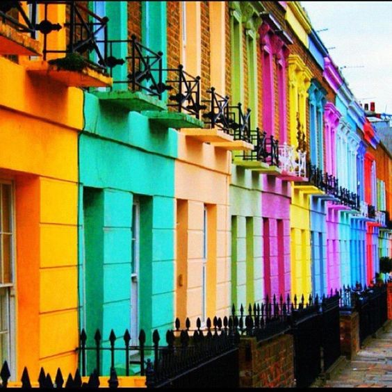 Colorful row houses with rainbow painted facades and black iron railings lining a city street