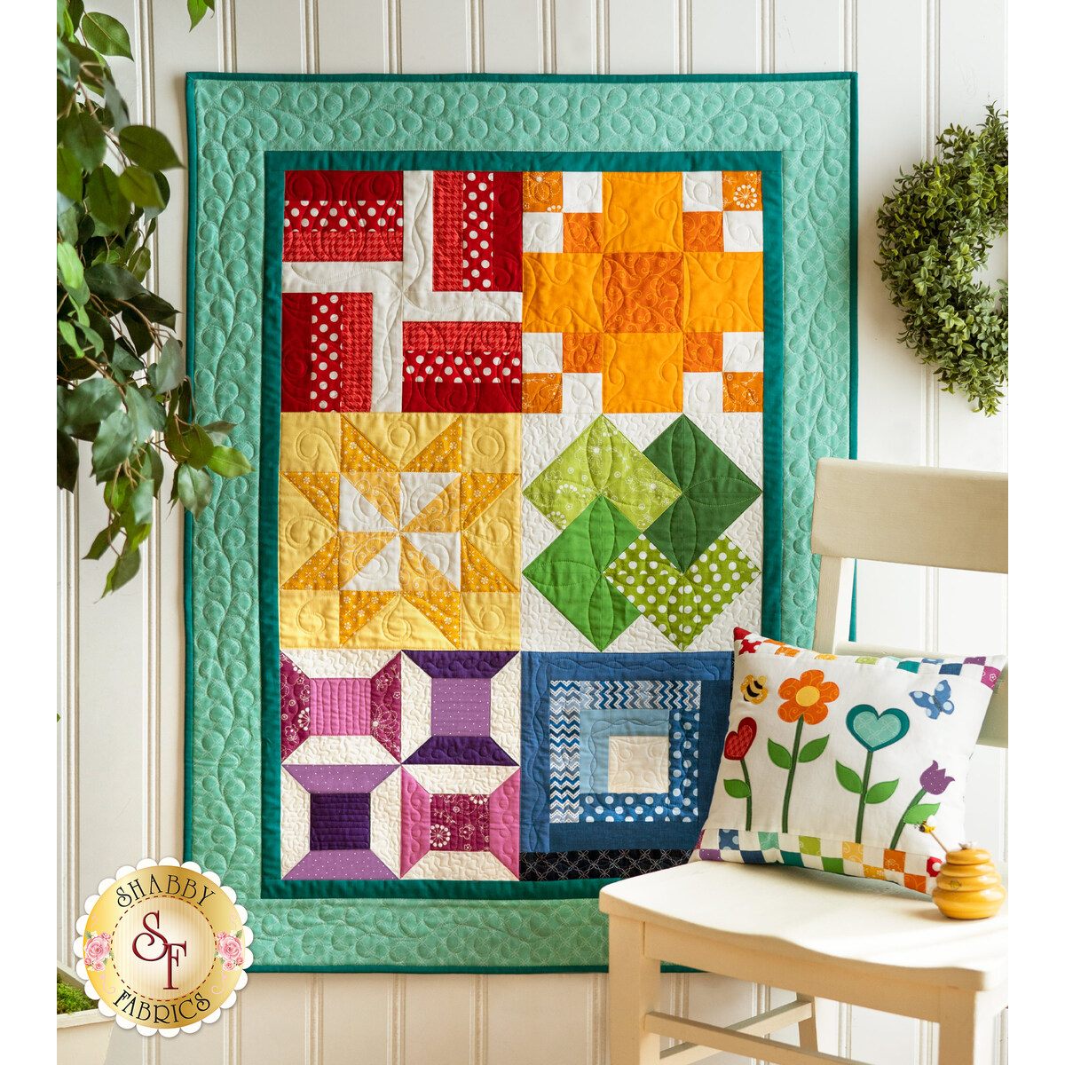 Rainbow sampler quilt with traditional blocks in red, orange, yellow, green, purple, and blue on turquoise background