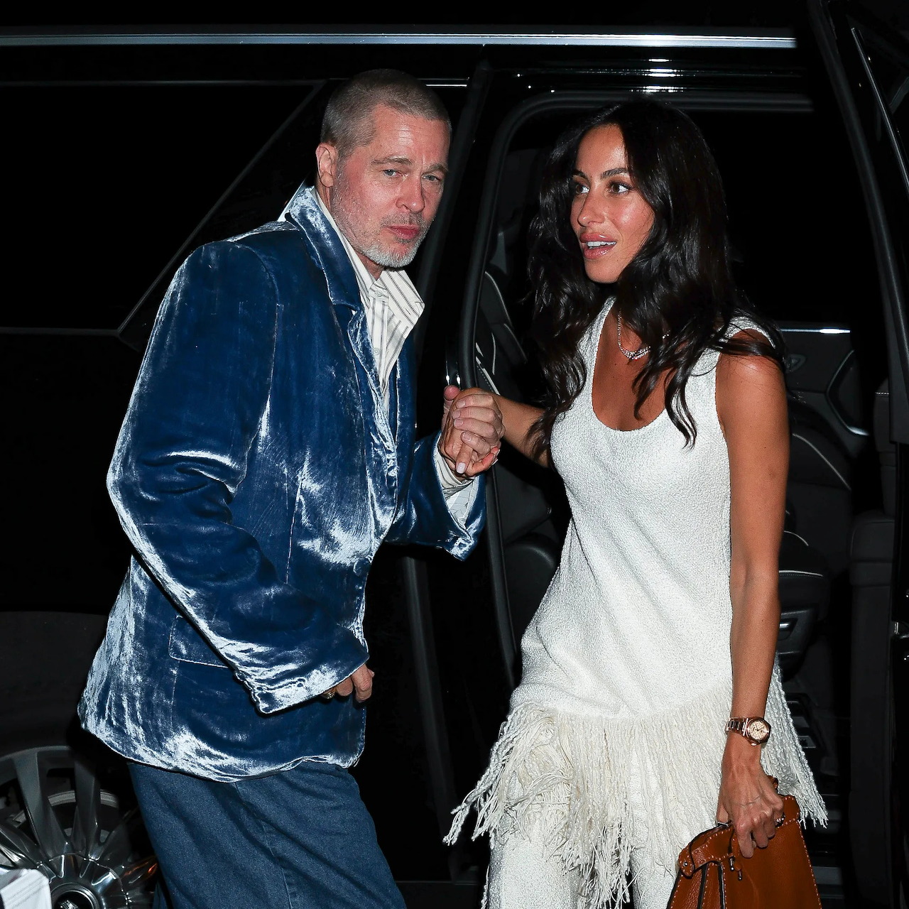 Man and woman standing beside a dark car at night