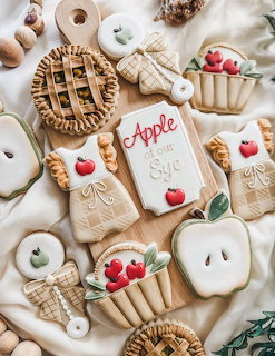Flat lay of apple-themed decorated sugar cookies including pie, basket, and apple slice shapes