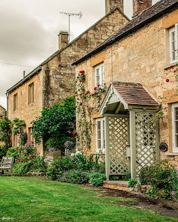Stone cottage with garden archway and flowering plants in front yard